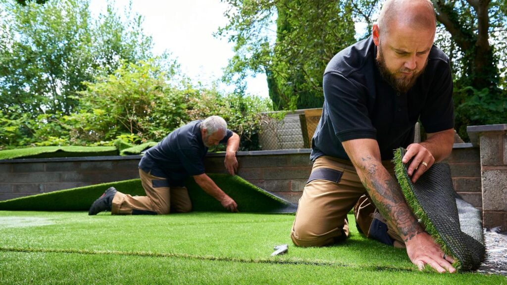 Workers installing artificial grass in backyard