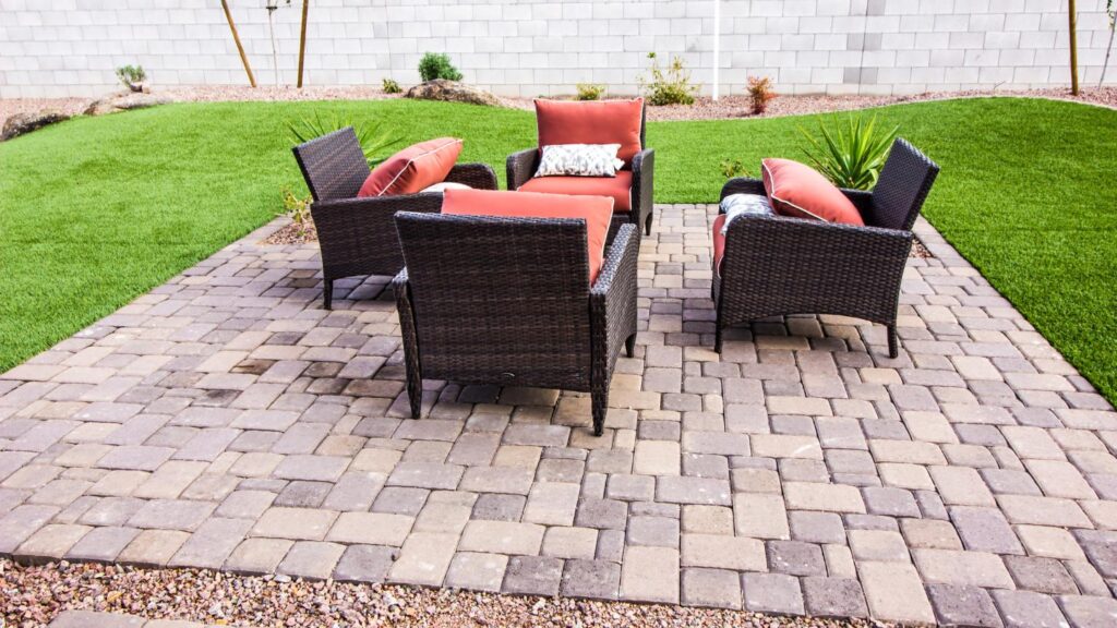 Wicker patio furniture with orange cushions on pavers