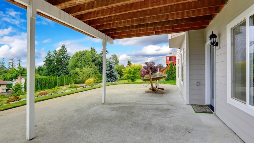 Covered patio overlooking landscaped backyard and lawn